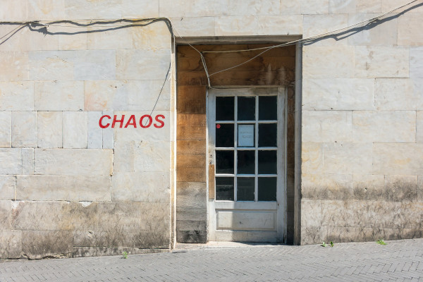 Porte dans un mur sur lequel est écrit en rouge le mot chaos